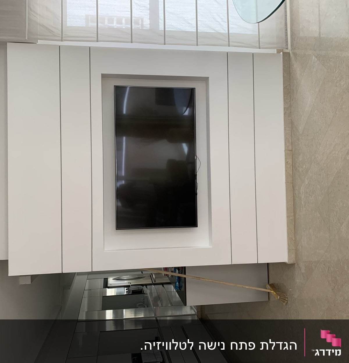 קיר גבס עם טלוויזיה מובנית ומטאטא על הרצפה
